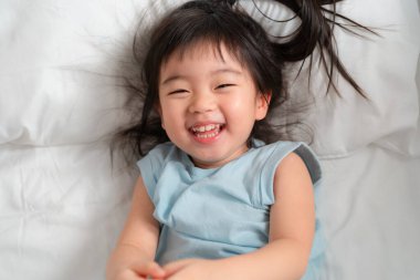 Parlak bir gülümsemesi olan neşeli genç bir kız, yumuşak doğal ışıkta neşe ve masumiyet sergiliyor. Neşeli saçları hoş sahnelere ekleniyor..