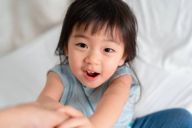 Işıl ışıl gülümseyen küçük bir çocuk ev ortamındaki rahat ortama uzanır, neşe ve masumiyeti somutlaştırır. Neşeli enerjisi çocukluk bağının ve bağlantının özünü yakalıyor..