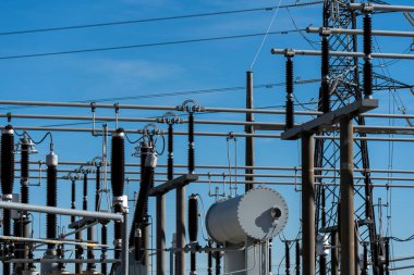 Mavi gökyüzünde elektrik pilonu ve kabloları olan tehlikeli yüksek voltajlı elektrik santrali.