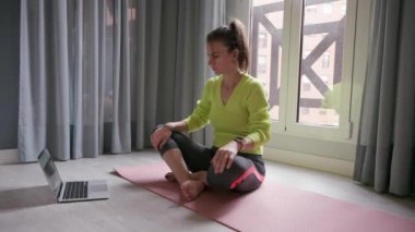 Çekici esmer kadın video rehberli bir yoga sınıfının talimatlarına dikkat ediyor. Yüksek kalite 4k görüntü