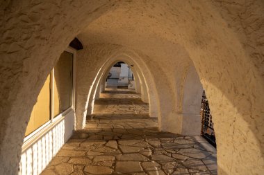 Sabahın erken saatlerinde otel binasının önünde asfaltlı zemin ve alçı duvarlı güneşli kemer yolu.