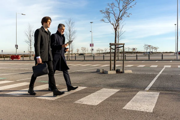 Full body of confident businessmen in formal clothes walking on crosswalk while having discussion during meeting