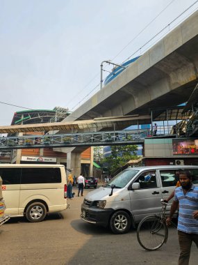 Mirpur, Dhaka, Bangladeş - 03.20.2023: Mirpur 10 otobüs durağı ve yeni inşa edilen metro istasyonu arka planda. Dhaka şehri kalabalığı