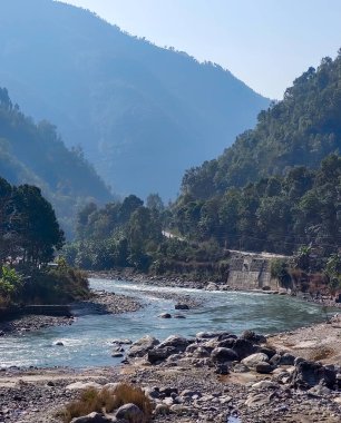Arka planda tepelerin manzaralı Sunkoshi nehrinin güzel sabah manzarası. Nepal 'de mavi su ve kayalarla güzel bir tepe nehri.