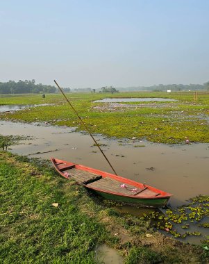 Bangladeş 'in kırsal kesimindeki bir köyde nehir kıyısında konuşlanmış boş bir tekne. Güney Asya köyü nehir ve teknesi