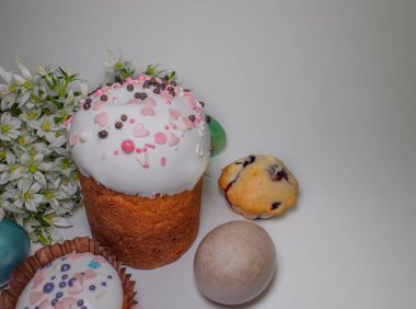 Geleneksel pasta ile süslenmiş Paskalya durgun hayatı üzerine krema ve serpiştirme, boyalı yumurta, beyaz çiçekler, ve hafif arka planda küçük bir çilekli kek