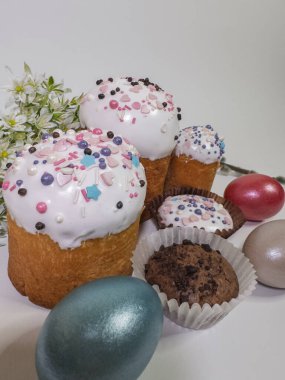 Geleneksel Paskalya pastalarına yakın plan beyaz kremalı, renkli serpiştirmeli, boyalı yumurtalı ve çiçekli. Ortodoks Paskalya kutlamaları için ev yapımı şenlikli pasta.