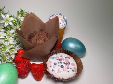 Çikolatalı kek, dekore edilmiş kek, boyanmış yumurta, kurumuş çilek ve beyaz bahar çiçekleriyle süslenmiş Paskalya kompozisyonu.