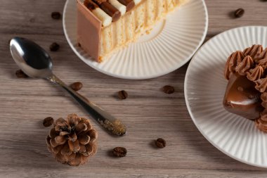 Bir fincan espresso, tarçın çubuğu, çam kozalağı ve doğal ışık altında yıkanmış ahşap bir masanın üzerine serpiştirilmiş kahve çekirdekleri içeren rahat, rustik bir kahve sahnesinin yukarıdan çekimi.