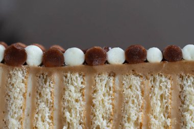 Üzerinde çikolata ve vanilya süslemeleri bulunan katmanlı bir pastanın detaylı yakın plan resmi, desen ve tasarımı vurgulanıyor.