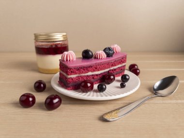 İçinde pembe kremalı bir dilim çilekli pasta ve taze böğürtlenlerle süslenmiş bir kavanoz cheesecake ve hafif ahşap bir yüzeyde kaşıkla güzel bir tatlı sahnesi. Gurme yemek içeriği için mükemmel