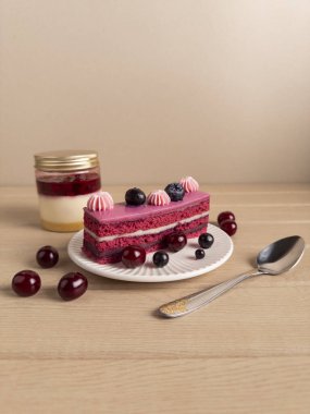 Bir dilim çilekli pasta pembe kremalı ve beyaz bir tabakta taze böğürtlenler kavanozdaki tatlının yanında ve altın sarısı olan gümüş bir kaşık. Hafif ahşap üzerine kurulmuş, canlı ve yemek içeriği için ideal.