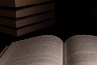 Arka planda bir yığın kitap olan açık bir kitabın kapanış sahnesi. Eğitim, okuma, öğrenim ya da edebiyat temalı görseller için ideal