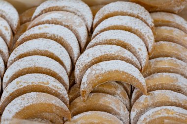 Ahşap bir yüzeye dizilmiş taze pişmiş, hilal şeklinde, toz şekerli kurabiyelerin yakın plan çekimi. Ev yapımı hamur işleri, tatlılar ve tatil ziyafetleri için mükemmel.