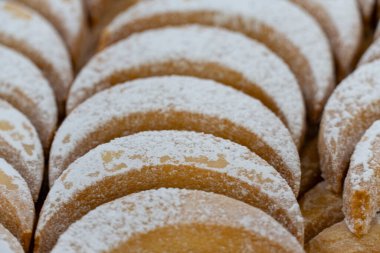 Ahşap bir yüzeye dizilmiş taze pişmiş, hilal şeklinde, toz şekerli kurabiyelerin yakın plan çekimi. Ev yapımı hamur işleri, tatlılar ve tatil ziyafetleri için mükemmel.