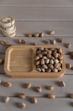 Tahta bir tepside, ahşap bir yüzeye serpilmiş, doğal dokuları ve toprak tonlarını ön plana çıkaran, kırsal kabuklu şam fıstığı manzarası.