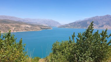 Berrak mavi gökyüzünün altında engebeli tepeler ve yemyeşil yemyeşil ile çevrili turkuaz bir dağ gölü nefes kesici bir manzara. Doğa aşıkları ve maceracılar için mükemmel bir yer.
