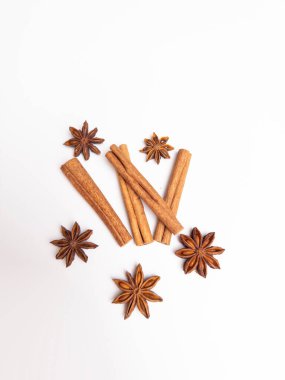 Tarçın çubukları ve yıldız anason kapsüllerinin temiz beyaz bir arkaplanda düzgün bir şekilde sıralandığı göz alıcı bir kompozisyon. Sıcak, doğal tonlar onu mutfak temalı projeler için ideal bir görüntü oluşturuyor.