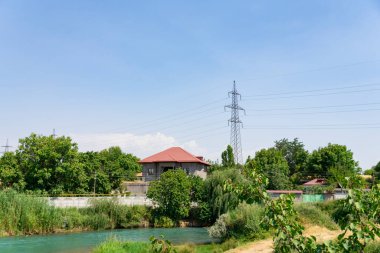 Bereketli yeşillik ve berrak mavi gökyüzünün altındaki evler tarafından çerçevelenmiş huzurlu turkuaz nehri