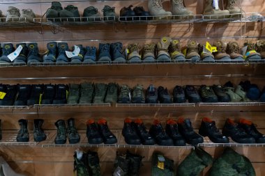 Taşkent, Özbekistan, 26 Temmuz 2025: Bir perakende mağazasında kamuflaj teçhizatı ile metal raflarda taktik ve askeri tarzda botların çeşitlendirilmesi