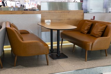 Kahverengi deri koltukları, ahşap masası ve şık tasarımı olan rahat, modern bir kafe. Restoran, dinlenme odası veya kahve dükkanı atmosferi için ideal bir konsept.