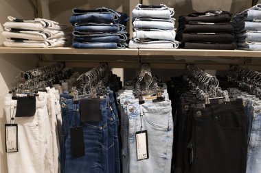 Bir giyim mağazasındaki ahşap raflarda düzgünce dizilmiş mavi kot yığınları, perakende satış ve satış konsepti sergileniyor.