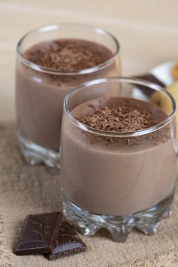 Cam bardaklarda çikolatalı pudingle servis edilen nefis ev yapımı kurabiyeler, üstüne de rendelenmiş siyah çikolata. Ahşap masada sıcak tatlı kompozisyonu