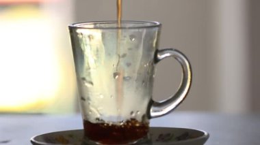 Güneşli bir günde tansent cam bardağa sıcak çay dökmek.