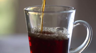 Güneşli bir günde tansent cam bardağa sıcak çay dökmek.