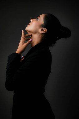 Klasik siyah takım elbiseli uzun boylu bir kadın modelin çarpıcı bir solo görüntüsü. Gösterişli çizgiler ve cilalı görünüş, resmi monokrom giyiminin zarafetini, güzelliğini ve çok yönlülüğünü vurguluyor. Uzun ve çarpıcı bir kadın modeli şık bir siyah takım elbise içinde poz veriyor. Şey...