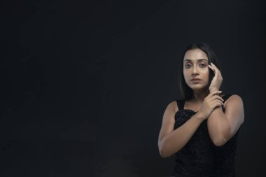 Uzun siyah saçlı, açık tenli, siyah etekli, yalnız bir manken.