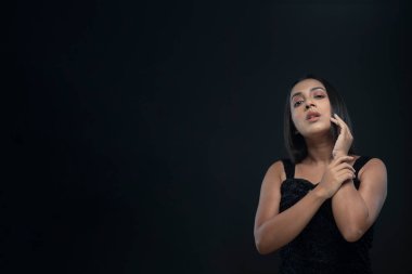 Uzun siyah saçlı, açık tenli, siyah etekli, yalnız bir manken.