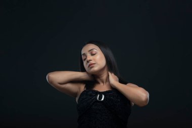 Siyah etek giyen, uzun siyah saçlı, yalnız bir kadın manken.