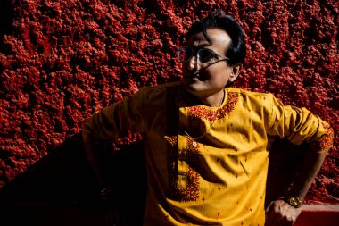 Hintli bir adam geleneksel Bengali kırmızı dhoti ve turuncu kurta giyiyor. Kolkata sokaklarında çekimler için poz veriyorlar.