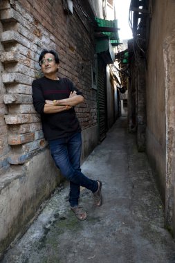 Sokakta poz veren mavi kot giyen bir adam.