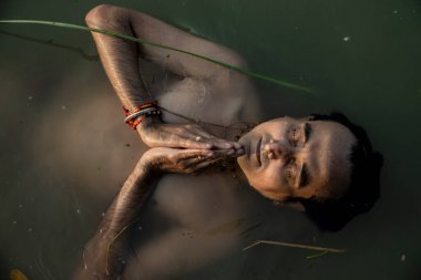 Hintli bir adam sabahın erken saatlerinde Ganj nehrine dalıyor. Göğsü suya gömülü ve Tanrı 'ya dua ediyor..