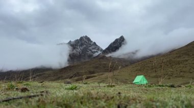 Ön planda küçük yeşil bir çadırla bir dağı kaplayan sisin zamanı. Jomolhari Ana Kamp Yürüyüşü, Butan