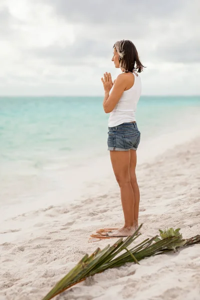 a fit adult woman with a sporty figure stands on Sadhu boards during yoga practice, concentration meditation, on a sandy sea beach