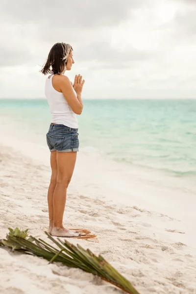 a fit adult woman with a sporty figure stands on Sadhu boards during yoga practice, concentration meditation, on a sandy sea beach
