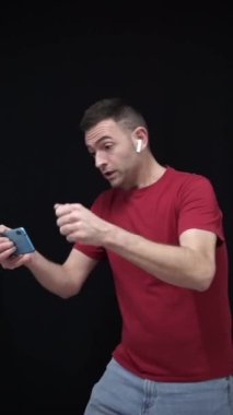 Ulusal takım taraftarı kırmızı t-shirt giyip cep telefonuyla Dünya Kupası maçını izlerken hayal kırıklığına uğradı ya da maçı kaybetti. 2022 Katar. Yüksek kaliteli görüntüler