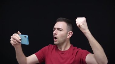Milli takım taraftarı kırmızı t-shirt giyip cep telefonuyla Dünya Kupası 'nı izlerken 2022 Katar şampiyonasını mutlu bir şekilde kutluyor. Yüksek kaliteli FullHD görüntüler