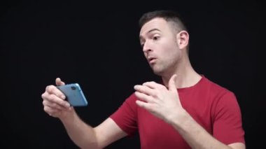 Beyaz adam kırmızı t-shirt giyip cep telefonuyla uluslararası turnuva maçını izliyor ve golü coşkuyla kutluyor. 2022 Katar ülkesinde. Yüksek kaliteli FullHD görüntüler