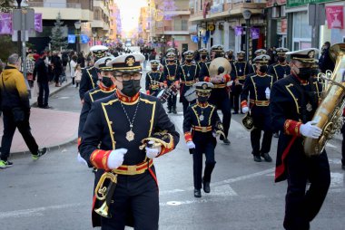 Ibi, İspanya - 5 Ocak 2022. Bilge adamların geçit törenine eşlik etmek için Noel şarkıları çalan mutlu müzisyen. Epifani arifesi geleneği.