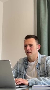 Beyaz adam evde laptopta çalışıyor. Aman Tanrım ve facepalm diyor. Dikey 4K. Günlük kot pantolon beyaz tişört. Yüksek kaliteli FullHD görüntüler