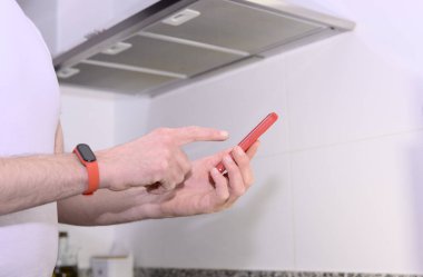 Genç teknisyenlerin orta kısmı mutfaktaki kaputun yakınında akıllı telefon kullanıyor.