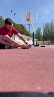 Yetişkin beyaz ayaklı, çıplak ayaklı basketbolcu kırmızı tişört giyip kazadan dolayı acı dolu bir yüz ifadesi ile çığlık atıyor. İltihaplı eklem. Şişmiş eklem. Dikey 4K 60fps video kaydı