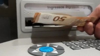 Bankamatiğe Euro olarak para yatıran birinin eli. 50 Euro 'luk banknot yığını. Yurt ekonomisi tasarrufu, ödeme kavramı. Katalan ve İspanyolca DEPOSIT metni. Yüksek kaliteli FullHD görüntüler