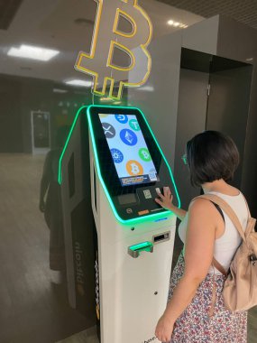 Alicante, İspanya - 29 Temmuz 2023. Orta yaşlı kadın kripto para birimine yatırım yapmak istiyor. Bitcoin ATM 'de alım-satım işlemi