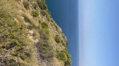 Villajoyosa 'daki Cala del Conill' den Benidorm Adası 'na gidiyoruz. Kavram: Güneşli bir günde deniz kenarı yaz tatili. Dikey 4k yavaş çekim görüntüsü