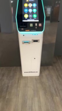 Alicante, İspanya - Temmuz 2023. Umumi bir yerdeki Bitbase ATM 'nin ön görüntüsü. Nakitten şifreli para almak için. Yatırım teknolojisi konsepti. Dikey 4 km yavaş çekim. Bitcoin, ada, cardano